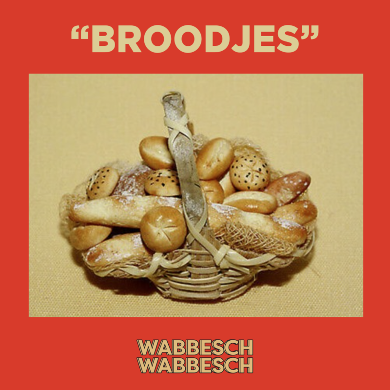 Artwork van Broodjes. Je ziet een foto van een mand gevuld met allerlei kleine broodjes. De achtergrond van de foto is beige, net als de titel van de aflevering "broodjes" en "wabbesch en wabbesch". De achtergrond van de foto is rood.
