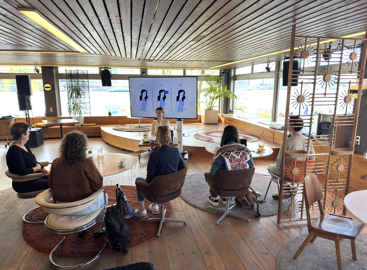 Foto van de cursus. Siona zit voor een groep met vijf deelnemers