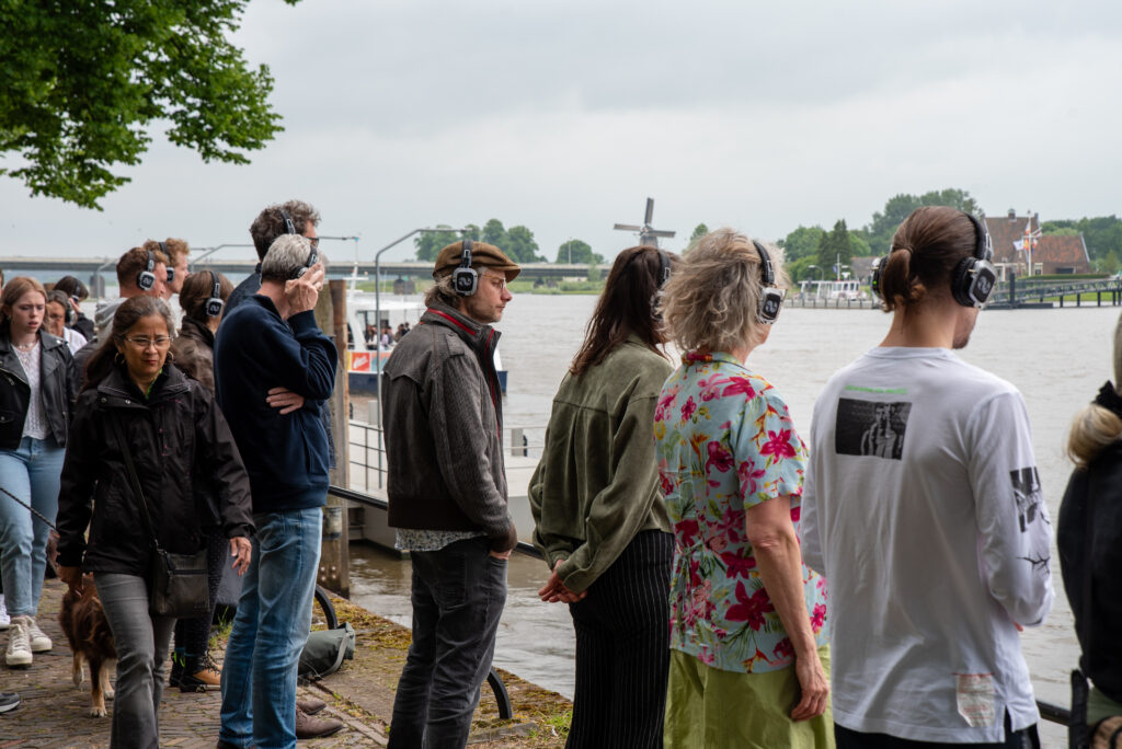 Groep mensen luistert met koptelefoon en kijkt naar water